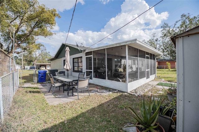 rear view of property featuring a patio, a sunroom, and a yard