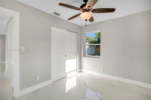 unfurnished bedroom with ceiling fan and a closet