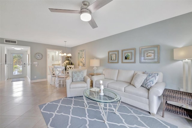 living area with ceiling fan with notable chandelier, light tile patterned flooring, visible vents, and baseboards