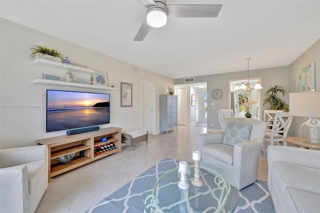 living area with light tile patterned floors, visible vents, and ceiling fan with notable chandelier