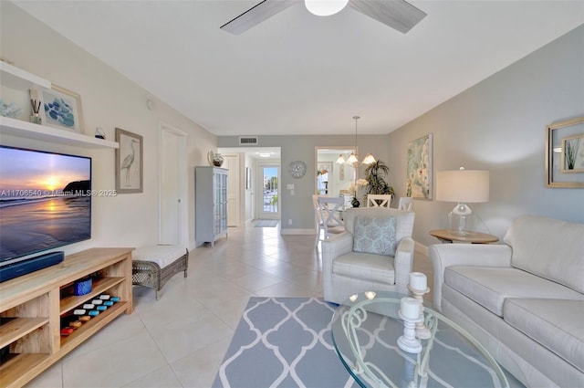 living area with light tile patterned floors, ceiling fan with notable chandelier, visible vents, and baseboards