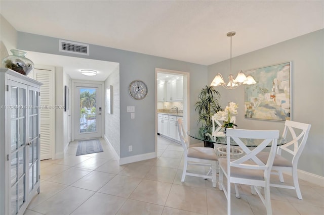 foyer entrance with light tile patterned floors, a chandelier, visible vents, and baseboards