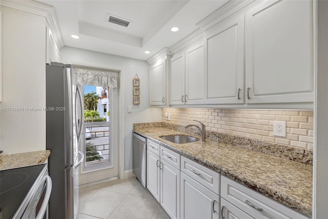 kitchen featuring a tray ceiling, visible vents, appliances with stainless steel finishes, white cabinetry, and a sink