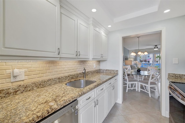 kitchen with light stone counters, light tile patterned floors, tasteful backsplash, white cabinets, and a sink