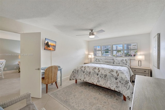 bedroom with light tile patterned floors, ceiling fan, baseboards, and a textured ceiling