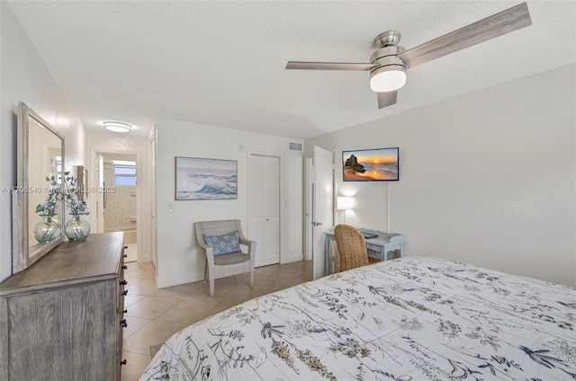 bedroom featuring light tile patterned floors, visible vents, ceiling fan, a textured ceiling, and baseboards