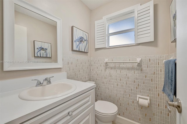 bathroom with a wainscoted wall, tile walls, toilet, and vanity