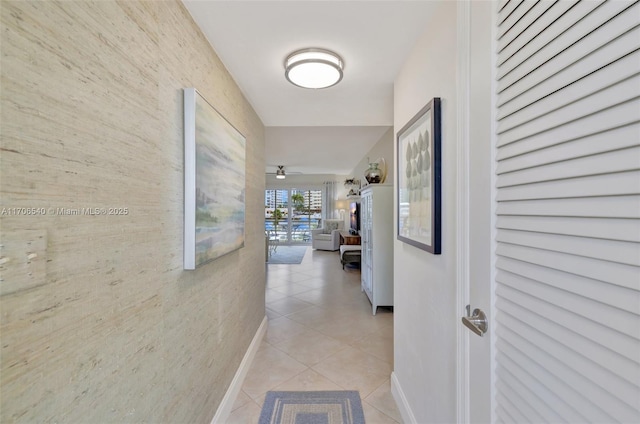 corridor with baseboards and light tile patterned floors