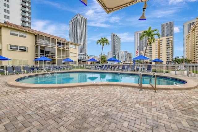 pool with a view of city, a patio area, and fence