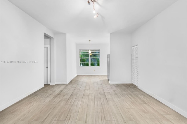 spare room featuring an inviting chandelier and light hardwood / wood-style flooring