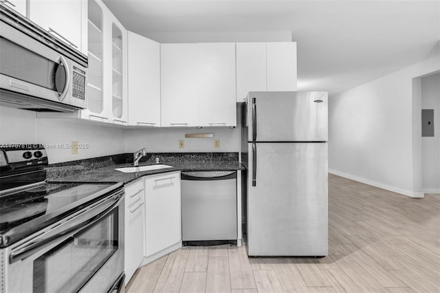 kitchen with white cabinetry, appliances with stainless steel finishes, sink, and dark stone countertops