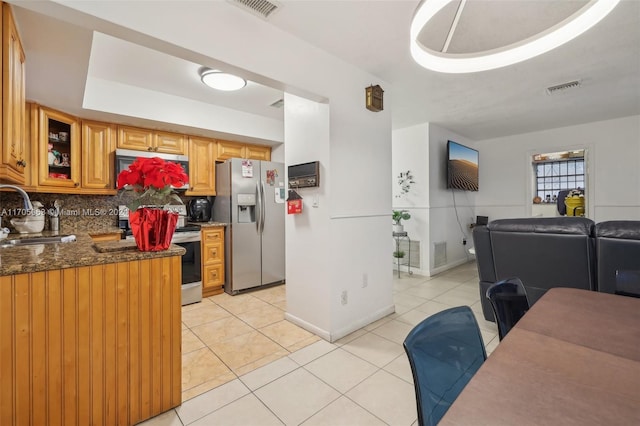 kitchen featuring appliances with stainless steel finishes, tasteful backsplash, light tile patterned floors, and sink