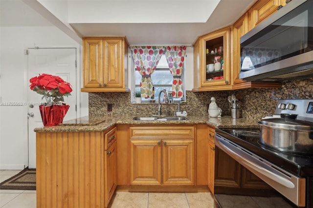 kitchen with sink, light tile patterned floors, stainless steel appliances, and stone countertops