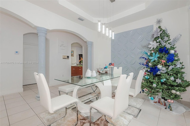 tiled dining room with decorative columns and a tray ceiling