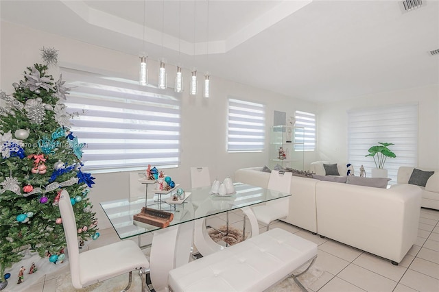 tiled dining space with a raised ceiling