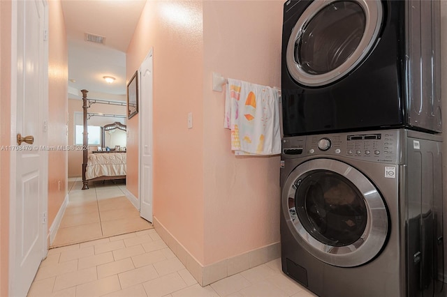 clothes washing area with stacked washer / dryer and light tile patterned flooring