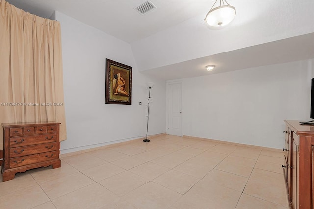 spare room with vaulted ceiling and light tile patterned flooring