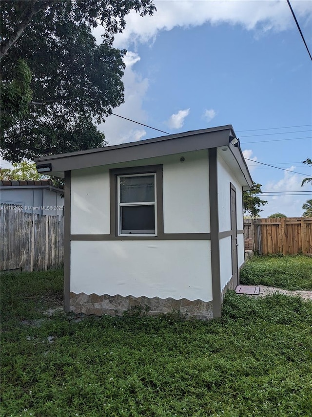 view of side of property featuring fence, a yard, and stucco siding