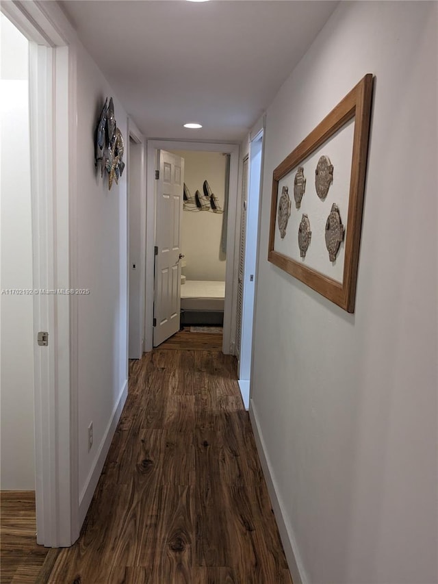 hallway featuring baseboards and dark wood-style flooring