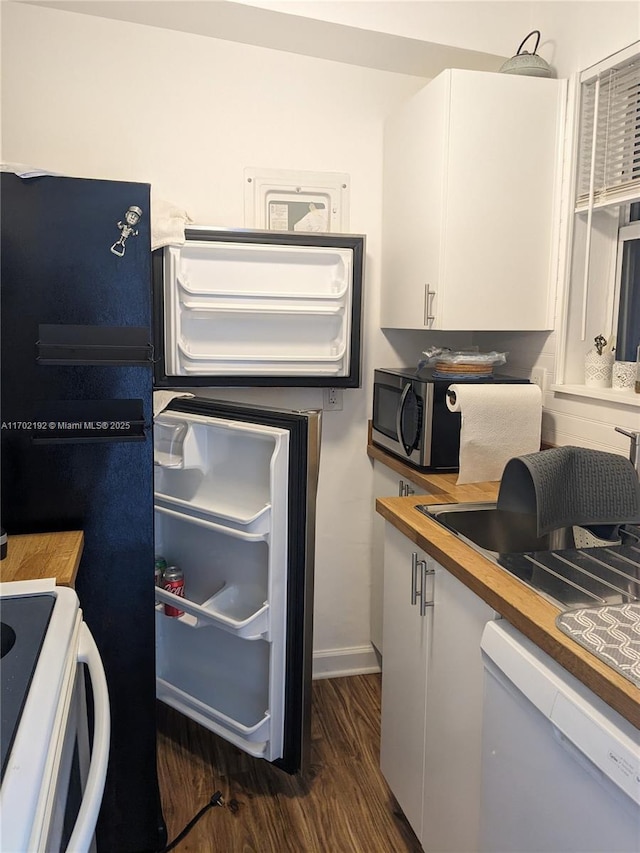 clothes washing area with baseboards, a sink, and dark wood finished floors