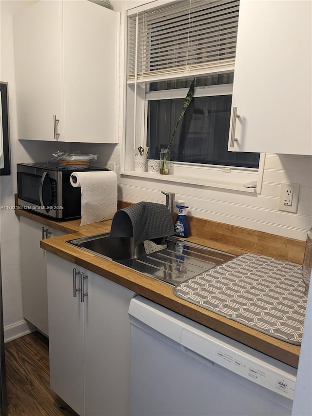 kitchen with dark wood-style floors, stainless steel microwave, baseboards, dishwasher, and wooden counters