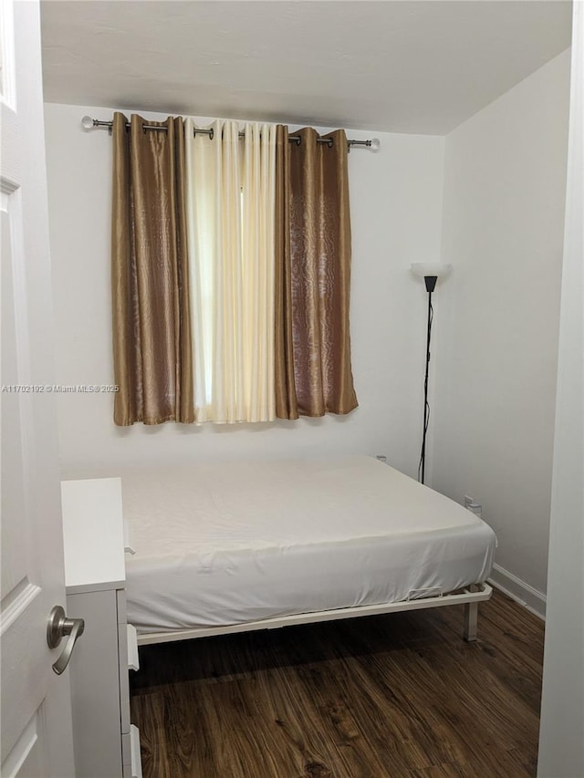 bedroom featuring baseboards and dark wood-style floors