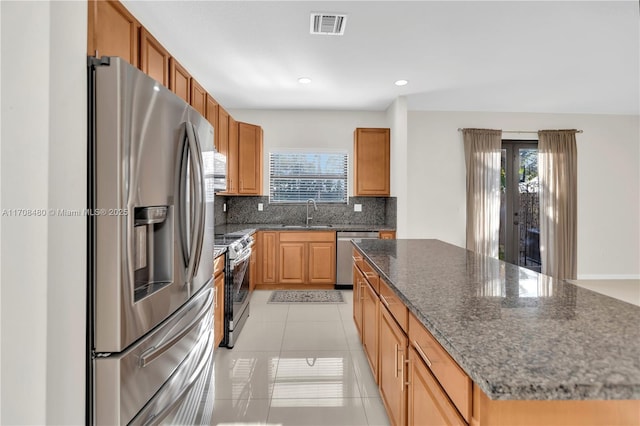 kitchen featuring stainless steel appliances, tasteful backsplash, visible vents, a healthy amount of sunlight, and a kitchen island