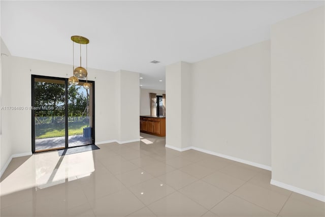 spare room featuring light tile patterned flooring, visible vents, and baseboards