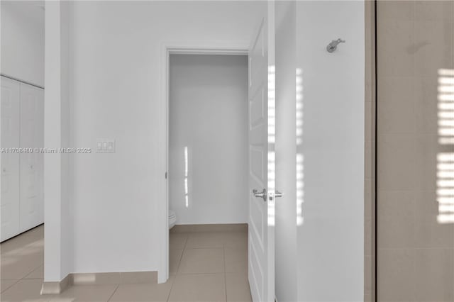 hallway featuring light tile patterned floors and baseboards