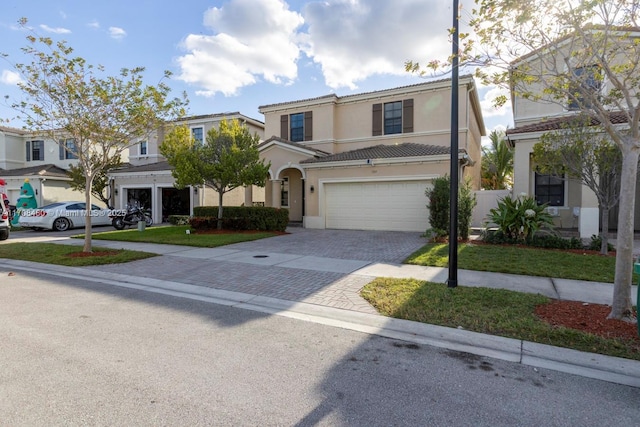 view of front of home with decorative driveway, a tiled roof, an attached garage, and stucco siding