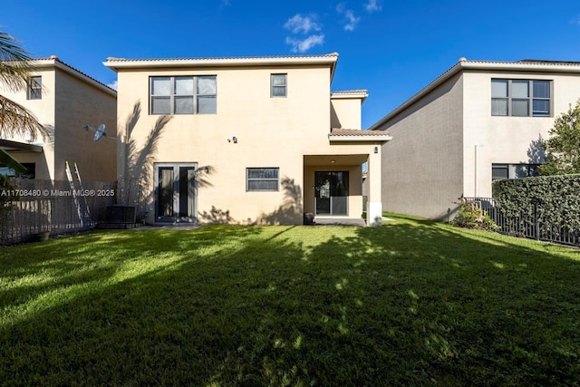 back of house with stucco siding, a yard, a tiled roof, and fence