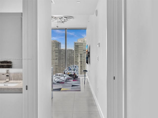 corridor with expansive windows, sink, and light tile patterned flooring