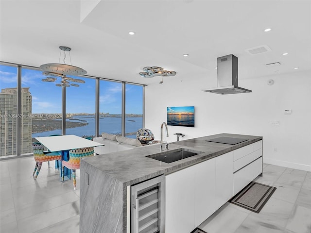 kitchen with white cabinetry, sink, island exhaust hood, plenty of natural light, and a water view