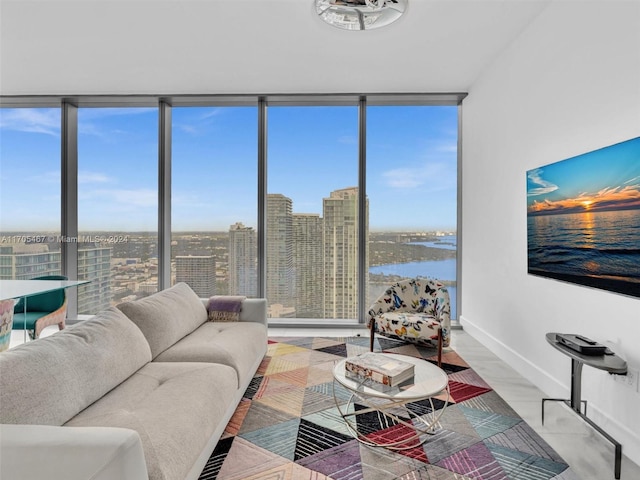 living room featuring plenty of natural light, a water view, and a wall of windows