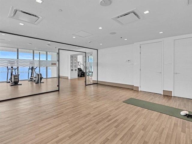 workout area with a wall of windows and light hardwood / wood-style flooring