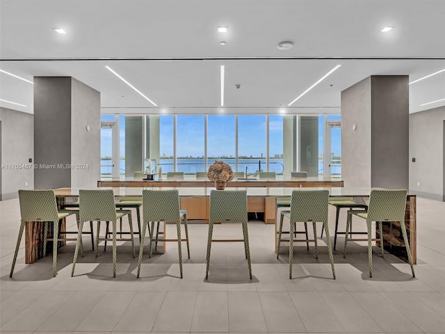 tiled dining area with a water view, floor to ceiling windows, and sink