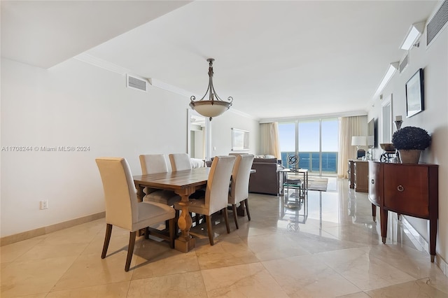 dining area featuring floor to ceiling windows, crown molding, and a water view