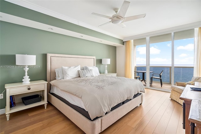 bedroom featuring access to exterior, ceiling fan, hardwood / wood-style flooring, a water view, and ornamental molding