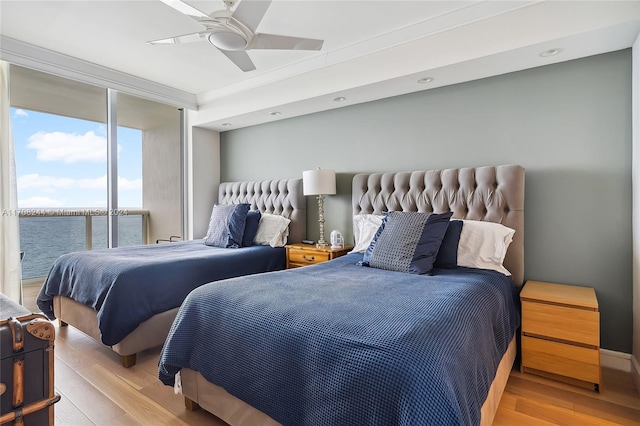 bedroom with ceiling fan, crown molding, a water view, and light hardwood / wood-style floors