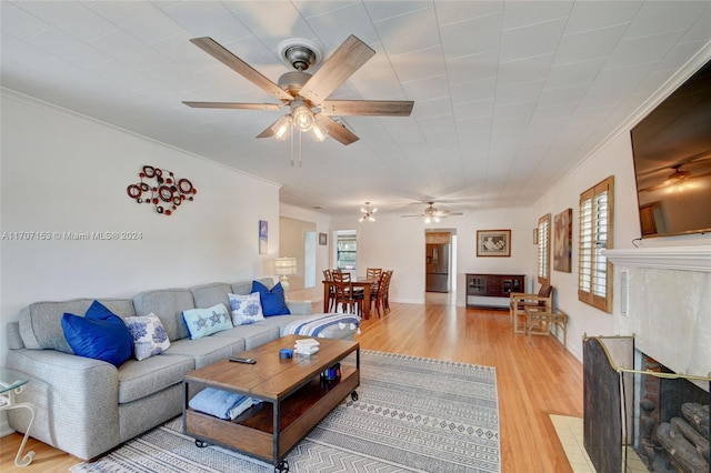 living room with light hardwood / wood-style flooring, ceiling fan, and crown molding