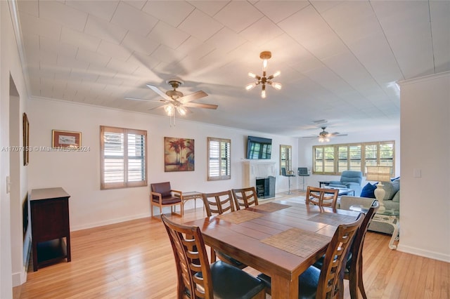 dining area with ceiling fan with notable chandelier, light hardwood / wood-style floors, and a wealth of natural light