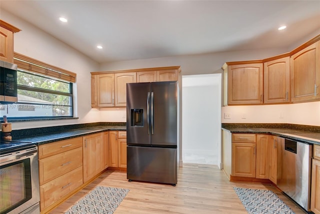 kitchen with stainless steel appliances, light brown cabinetry, and light hardwood / wood-style flooring