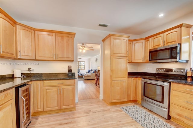 kitchen featuring dark stone counters, wine cooler, ceiling fan, appliances with stainless steel finishes, and light hardwood / wood-style floors