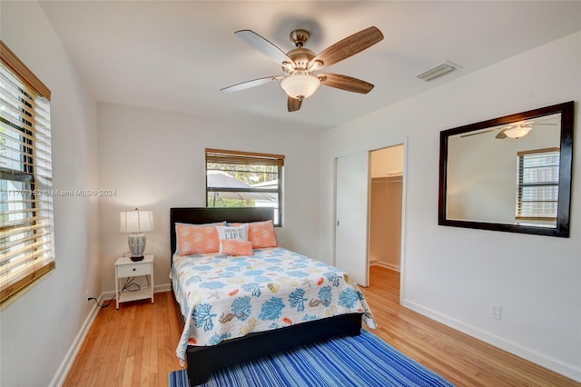 bedroom featuring a spacious closet, light hardwood / wood-style flooring, a closet, and ceiling fan