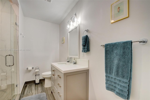 bathroom featuring hardwood / wood-style floors, vanity, toilet, and a shower with door