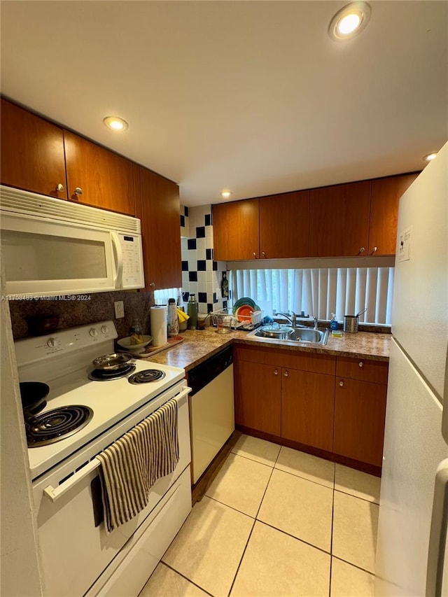 kitchen with decorative backsplash, light tile patterned floors, white appliances, and sink