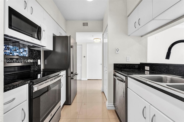 kitchen featuring white cabinetry, sink, light tile patterned floors, and appliances with stainless steel finishes