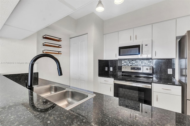 kitchen featuring dark stone counters, sink, decorative backsplash, white cabinetry, and stainless steel appliances