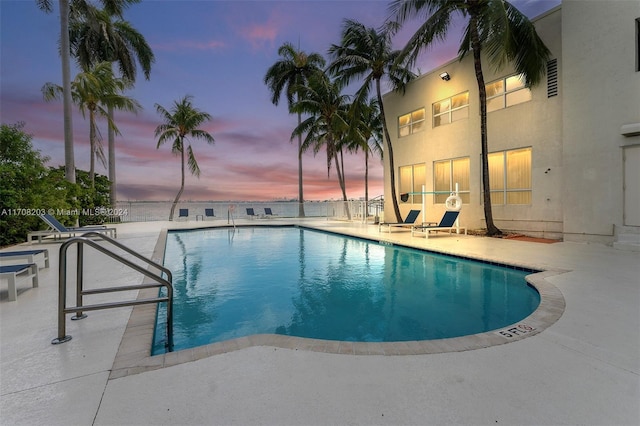 pool at dusk featuring a patio