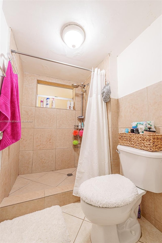 bathroom with a shower with shower curtain, tile patterned floors, tile walls, and toilet